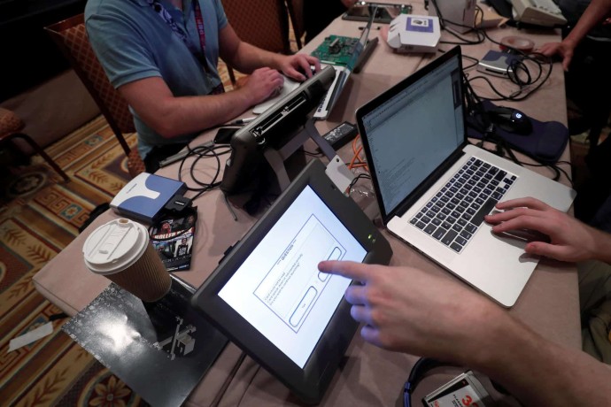 Hackers try to access and alter data from an electronic poll books in a Voting Machine Hacking Village during the Def Con hacker convention in Las Vegas